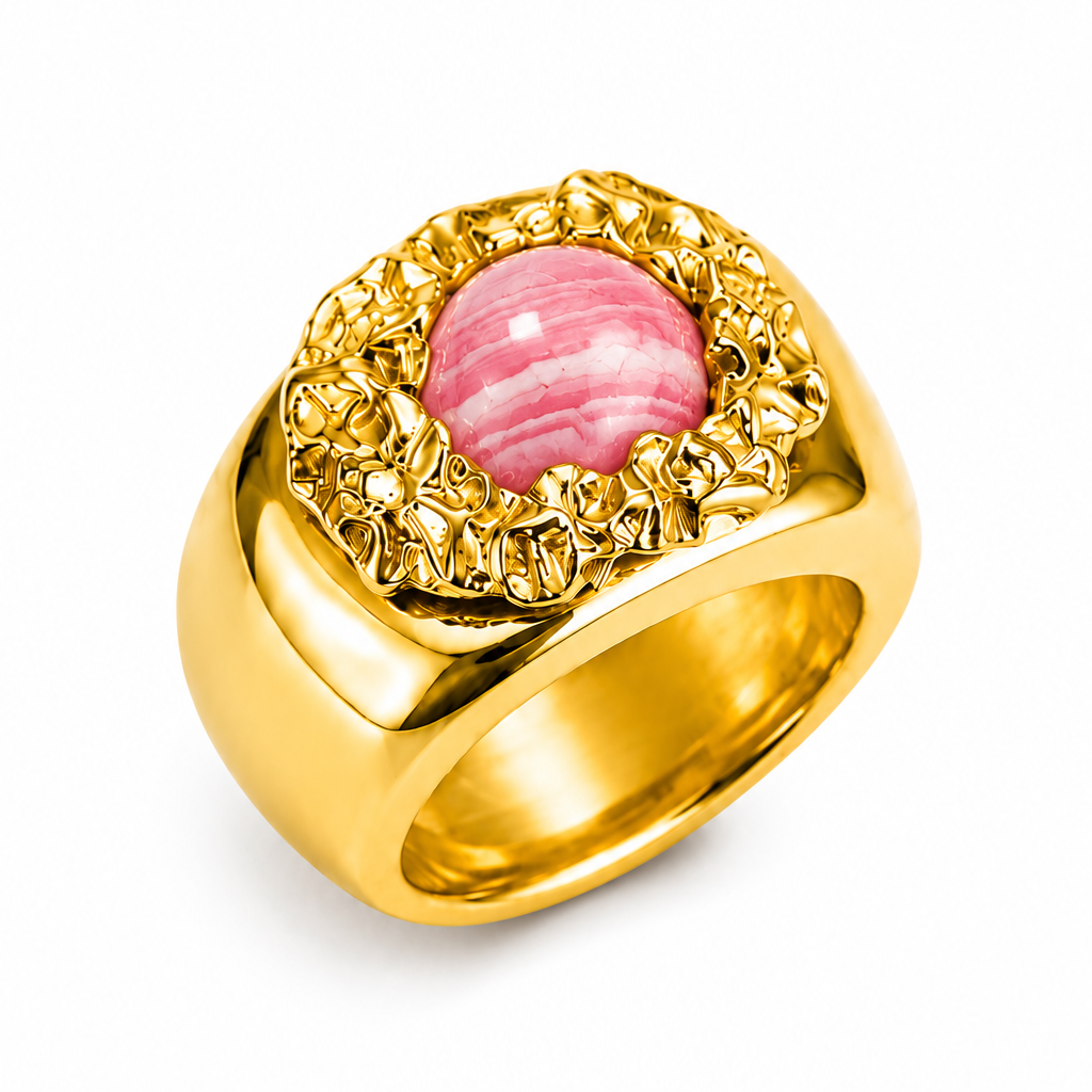 A gold signet-style ring featuring a round pink cabochon gemstone surrounded by a textured, scalloped gold bezel, set against a plain white background.