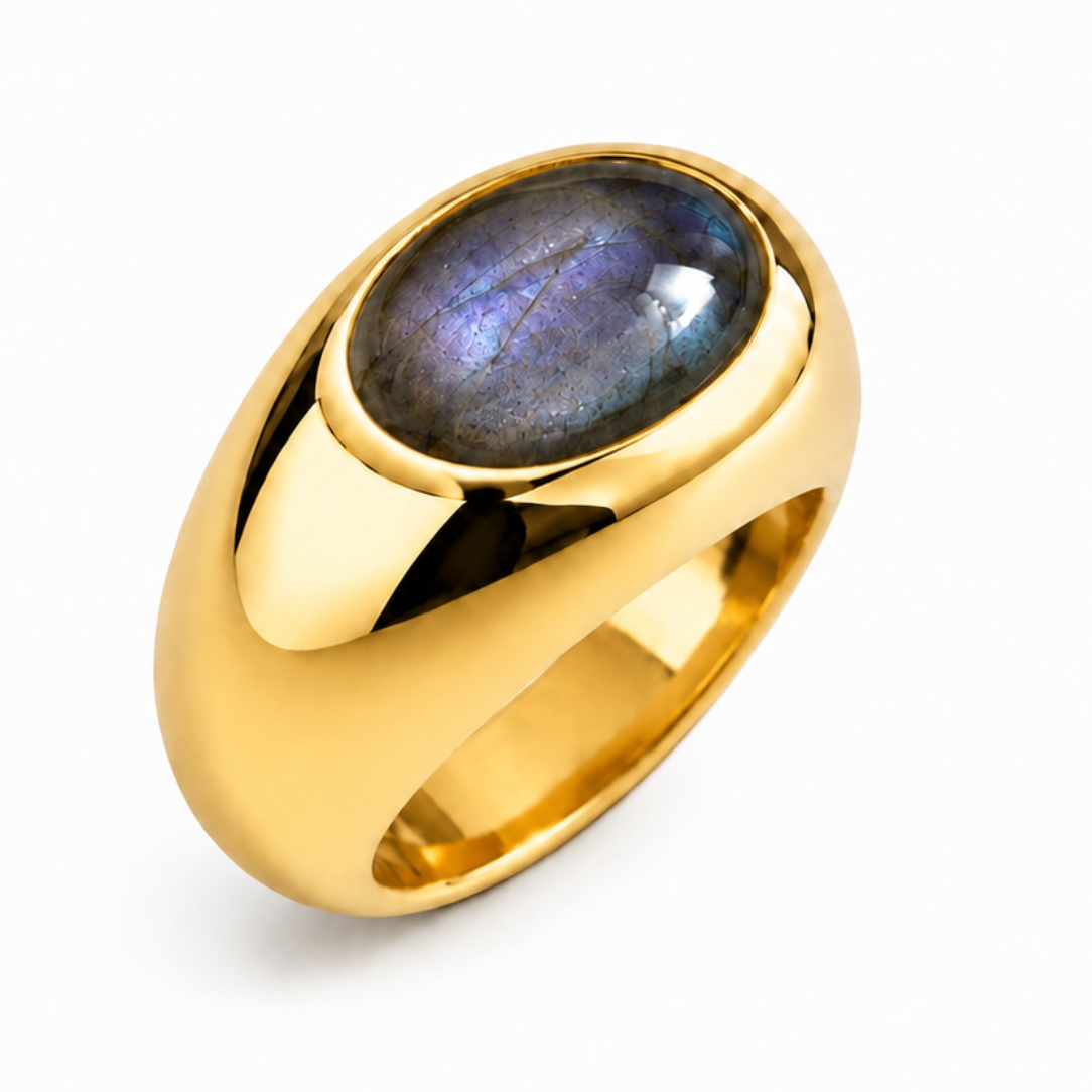 A polished gold signet-style ring featuring an oval cabochon gemstone with a blue-purple iridescent luster, set against a clean white background.